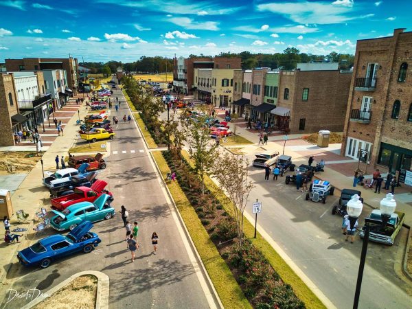 Aerial view of Southaven, MS Main Street bustling with classic cars, families, and local businesses under a bright blue sky — showcasing vibrant community life powered by dependable electrical infrastructure.