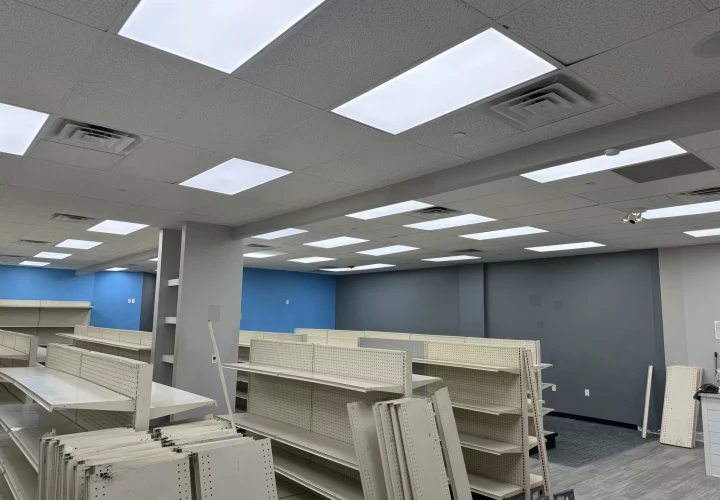 An empty commercial space prepared for fit-out, with shelving units in place and a newly installed ceiling with LED lights.
