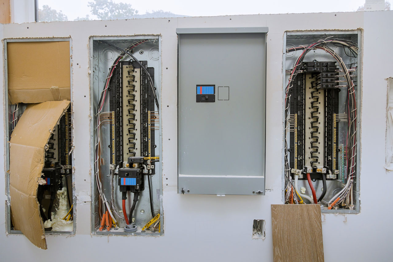 Three exposed electrical panels mounted during construction