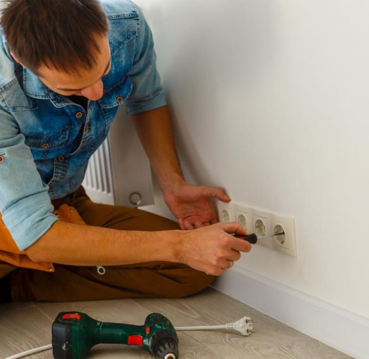 Electrician repairing a wall outlet