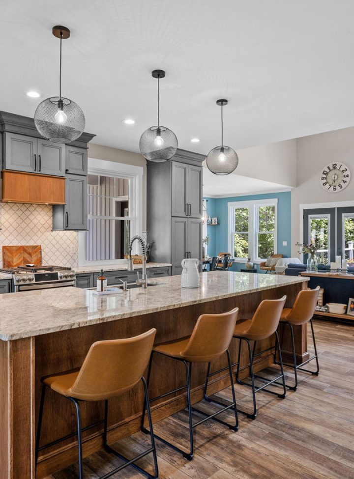 Bright, open-concept kitchen featuring pendant lights over a large island, recessed ceiling lighting, and stylish gray cabinetry — showcasing professional electrical installation.