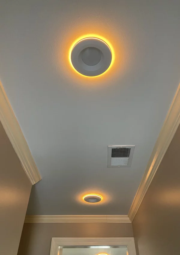 Ceiling view of a modern residential interior featuring two circular LED lights with a warm glow, set against a white ceiling.