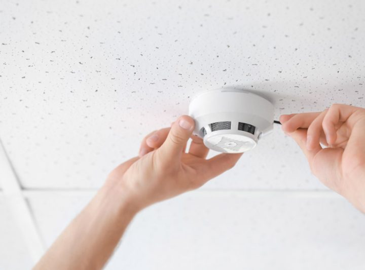 Closeup of electrician installing smoke detector on ceiling